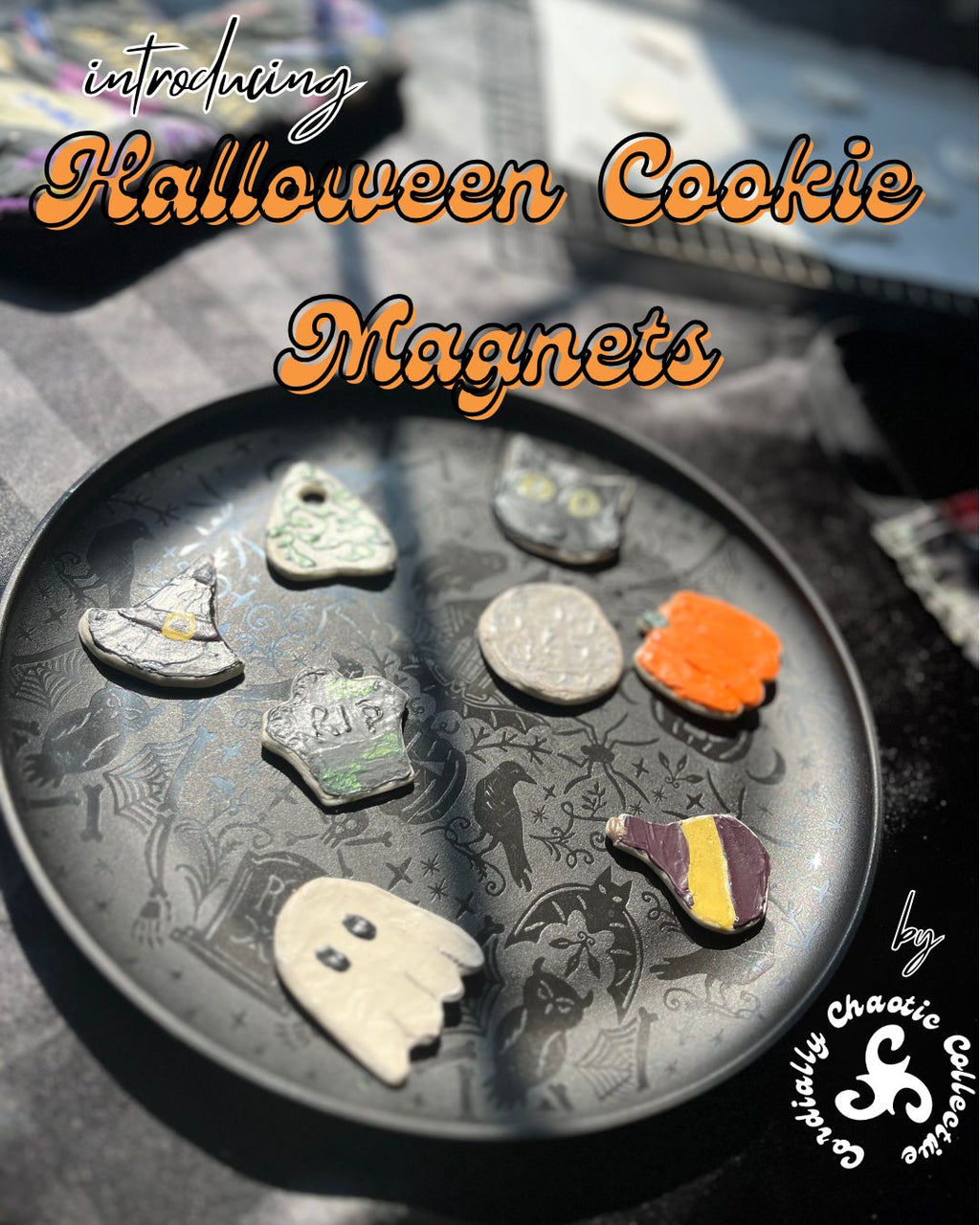 A promotional image showing several small Halloween-themed cookie magnets arranged on a dark round plate. The magnets include shapes like a witch hat, ghost, planchette, pumpkin, and potion bottle, with overlaid text reading 'introducing Halloween Cookie Magnets' and a creator signature/logo in the lower right.