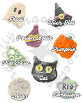 A set of Halloween-themed clay magnets shown on a white background, each labeled with its name: Ghost, Witch Hat, Potion Bottle, Pumpkin, Planchette, Cat, Moon, and Tombstone. The designs feature hand-painted details in black, orange, purple, green, and beige.